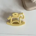 Vue détaillée d'une jolie pince à cheveux jaune clair en forme de cheval à bascule - Jaune