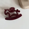 Gros plan sur la finition brillante d'une pince à cheveux bordeaux en forme de petit cheval - Bordeaux