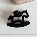 Vue détaillée d'une jolie pince à cheveux noire en forme de petit cheval à bascule. - Noir