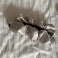 Detail einer eleganten champagnerfarbenen Satin-Bananenspange mit Strassakzenten. - Champagner