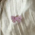 Close-up detail of a pink translucent bow hair clip with tiny rhinestones on fabric - Ribbon Bowknot / Pink
