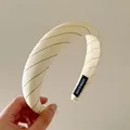 Detalle de una diadema de tela a rayas crema con una etiqueta tejida 'Handmade'. - Diadema de Rayas Amarillas y Negras