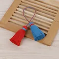 Gros plan détaillé de glands en coton rouge et bleu faits main sur un support en bambou - Gland à Double Extrémité / Rouge + Bleu Paon