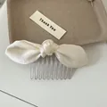 Detailed close-up of a cream-colored satin bow hair comb featuring elegant metal teeth - Creamy White Bow Hair Comb / Off White
