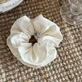 Detail shot of a cream satin hair scrunchie with delicate lace embroidery edges - 2# Off-White Scrunchie