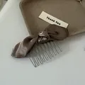 Macro detail of a coffee-colored satin bow hair comb with metallic teeth - Brown