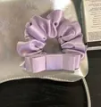 Κοντινό πλάνο κομψού μωβ σατέν scrunchie με λεπτομέρεια φιόγκου - Ροζ