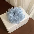 Nahaufnahme eines hellblauen Organza-Haargummis mit schimmernder Textur - Blau