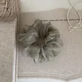 Elegantes olivgrünes Organza-Haargummi in der Detailansicht auf strukturiertem Leinen - Grün