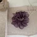 Nahaufnahme eines eleganten lila Organza-Haargummis auf rustikalem Segeltuch. - Lila