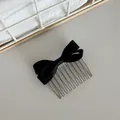Detailed view of a elegant black satin bow hair comb for stylish side hair styling - Black