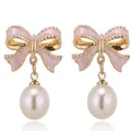 Dettaglio ravvicinato degli orecchini a fiocco in smalto rosa con perle eleganti - Rosa