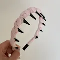 Detailed close-up of pink polka dot fabric headband with black teeth for hair styling. - Pink