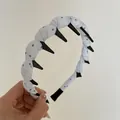 Detailed close-up of a blue polka dot fabric wrapped headband with black plastic long teeth - Blue
