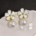 Close-up of white enamel flower and lustrous pearl on a vintage gold stud earring. - White