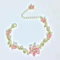 Primo piano di un elegante bracciale in oro con fiori di cristallo rosa e foglie - Rosa