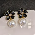 Macro view of exquisite black enamel flower earrings with elegant white pearl drops - Black