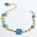 Dettaglio di un bracciale di lusso con fiori di strass blu e delicati motivi a foglia d'oro - Celeste