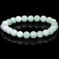 Detailed view of polished light green natural stone beads on a reflective surface - 21cm / 10mm / Burmese Jade