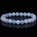 Close-up of polished light blue aquamarine beads on a reflective black surface bracelet - Transparent Aquamarine