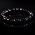 Detailed shot of a polished dark garnet crystal bead bracelet with mirror reflection - Garnet