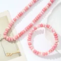 Gedetailleerde weergave van roze crackle kristallen kralenketting en armband set. - Ketting + Armband / Roze en Wit Rood Patroon