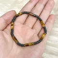 Detail shot of tiger eye cylinder bead bracelet with hematite spacers in hand - 4x13mm Cylinder Hematite Spacer / 19cm Bracelet