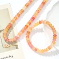 Close-up van de crackle kristallen kralen ketting en armband set in warme perziktinten - Ketting + Armband / Oranje