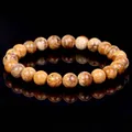Detail view of natural picture jasper stone bead bracelet on reflective surface - Jasper