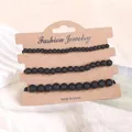 Nahaufnahme von drei schwarzen Lavastein-Armbändern auf einer Schmuckkarte aus Kraftpapier - Lavastein