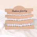 Detailansicht von drei weißen Opal-Naturstein-Perlenarmbändern auf Karte - Opal