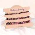 Nahaufnahme von pink Zebra- und schwarzen Steinperlen-Armbändern auf brauner Karte - Rhodonit mit schwarzen Linien