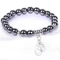 Close-up of dark metallic beads bracelet with an intricate silver Om symbol charm - 8mm Beads Om Pendant Style (B0027) / 19cm / Hematite