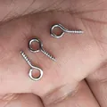 Small silver metal eye pins for DIY jewelry making shown on human palm for scale - 8x4mm / White K/Silver