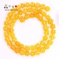 Detailed macro view of 8mm flat yellow flower glass beads for handmade DIY jewelry making - Approx 52 Pieces per Strand / Champagne