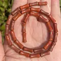 Macro detail of red jasper bamboo joint beads 5x12mm on palm with natural stone texture. - Bamboo Segment Red Stone / 5x12mm / Red Jasper