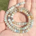 Detailed macro view of natural multicolor Amazonite rondelle stone beads held in palm - Irregular Shape / Abacus Amazonite 2x4mm