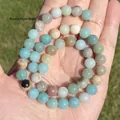 A detailed view of natural multi-colored Amazonite stone round beads held in palm - 4mm Approx 88pcs / Colorful Amazonite Round Beads