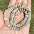 Close-up view of multi-colored natural Amazonite stone beads held in a person's palm. - Irregular Shape / Abacus Amazonite 4x6mm