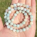 Detailed macro shot of natural Amazonite round stone beads with a matte finish on a palm. - 4mm Approx 88pcs / Matte Colorful Amazonite Round Beads