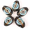 Macro detail of DIY cowrie shell beads featuring a vibrant blue and black evil eye pattern design - 10 Pieces Pack / Black Eye Black Shell
