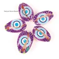Macro detail of purple cowrie shells with evil eye pattern for DIY jewelry making. - 10 Pieces Pack / Blue Eye Purple Shell