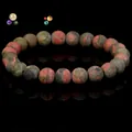 Premium natural unakite stone beaded bracelet displayed on a reflective black background - Unakite