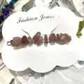 Detailed view of an irregular natural crystal stone hair clip on a white display card. - Strawberry Quartz