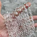 Gedetailleerde macro-opname van heldere natuurlijke Braziliaanse kristalkralen in de hand. - Licht Bewolkt (A765756) / 8x12mm (Ongeveer 32 stuks)