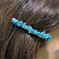 Close-up view of irregular natural blue crystal gravel on a sleek metal one-word hair clip. - Apatite