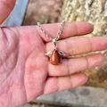Detail view of goldstone teardrop pendant with silver angel wings held in hand - Pendant Only (No Chain) / Gold Sandstone
