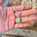 Detailed view of a green teardrop stone pendant with silver angel wings held in hand - Pendant Only (No Chain) / Green Aventurine
