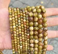 Close-up of various sizes of natural dragon blood stone round beads for DIY jewelry making - Golden Silk Jade