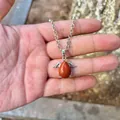 Detailed close-up view of a natural red jasper angel wing pendant necklace held in hand - Pendant Only (No Chain) / Red Jasper
